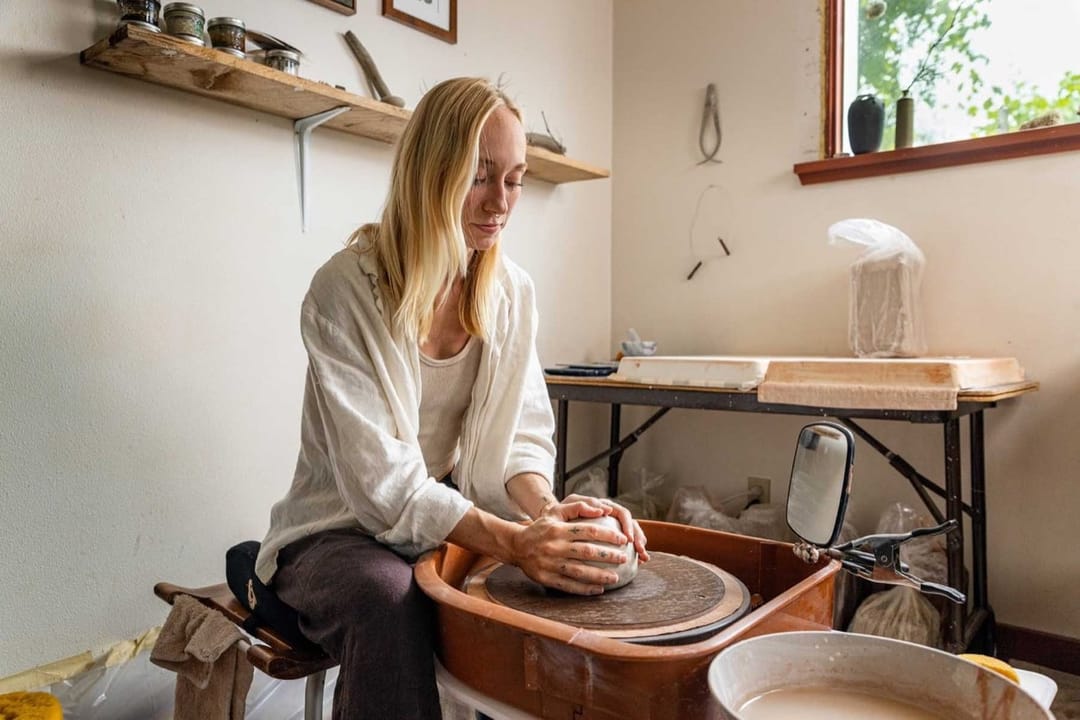 Alex Roby shaping clay on the pottery wheel in her studio
