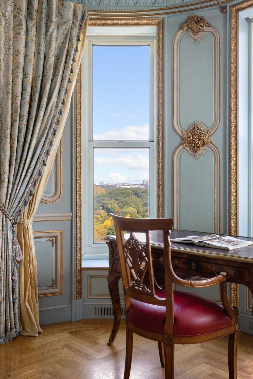 Reading nook with a red leather chair and gilded paneling, window onto Central Park