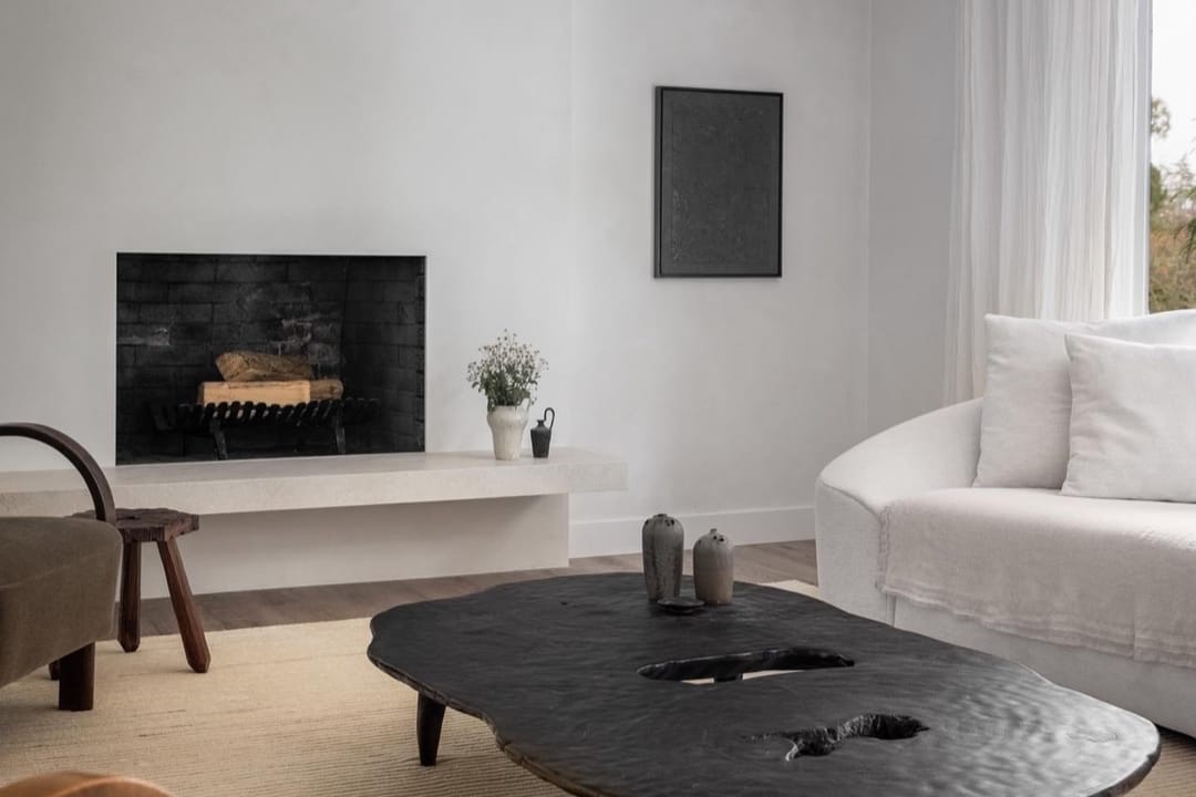 Minimalist living room with a sculpted black coffee table, a curved white sofa and a fireplace