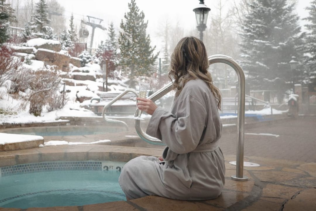 Guest in a robe at the outdoor hot tub in falling snow, Park Hyatt Beaver Creek