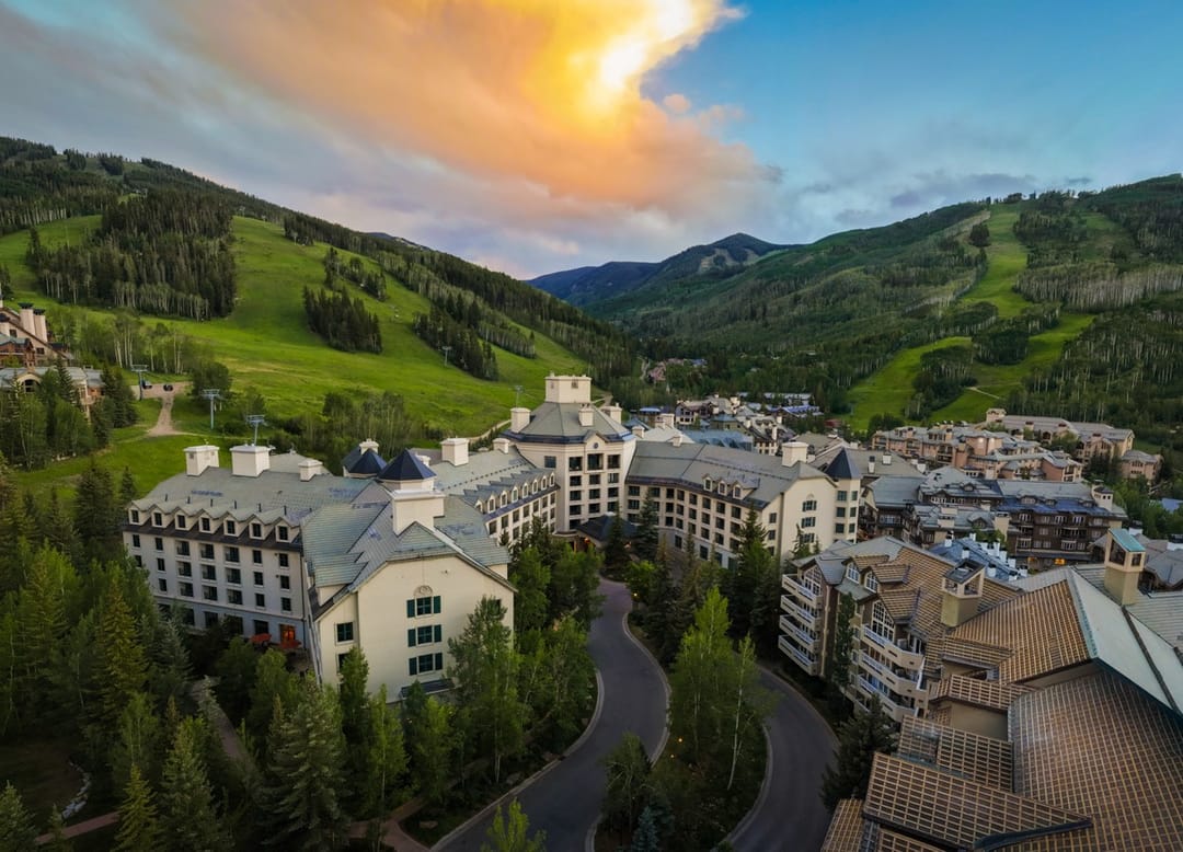 Park Hyatt Beaver Creek in its valley at sunset, green ski runs above