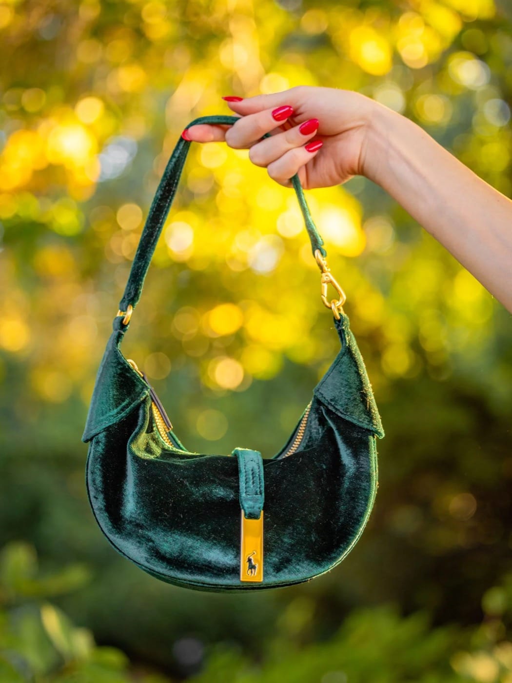 Green velvet Polo Ralph Lauren bag held up against golden fall leaves